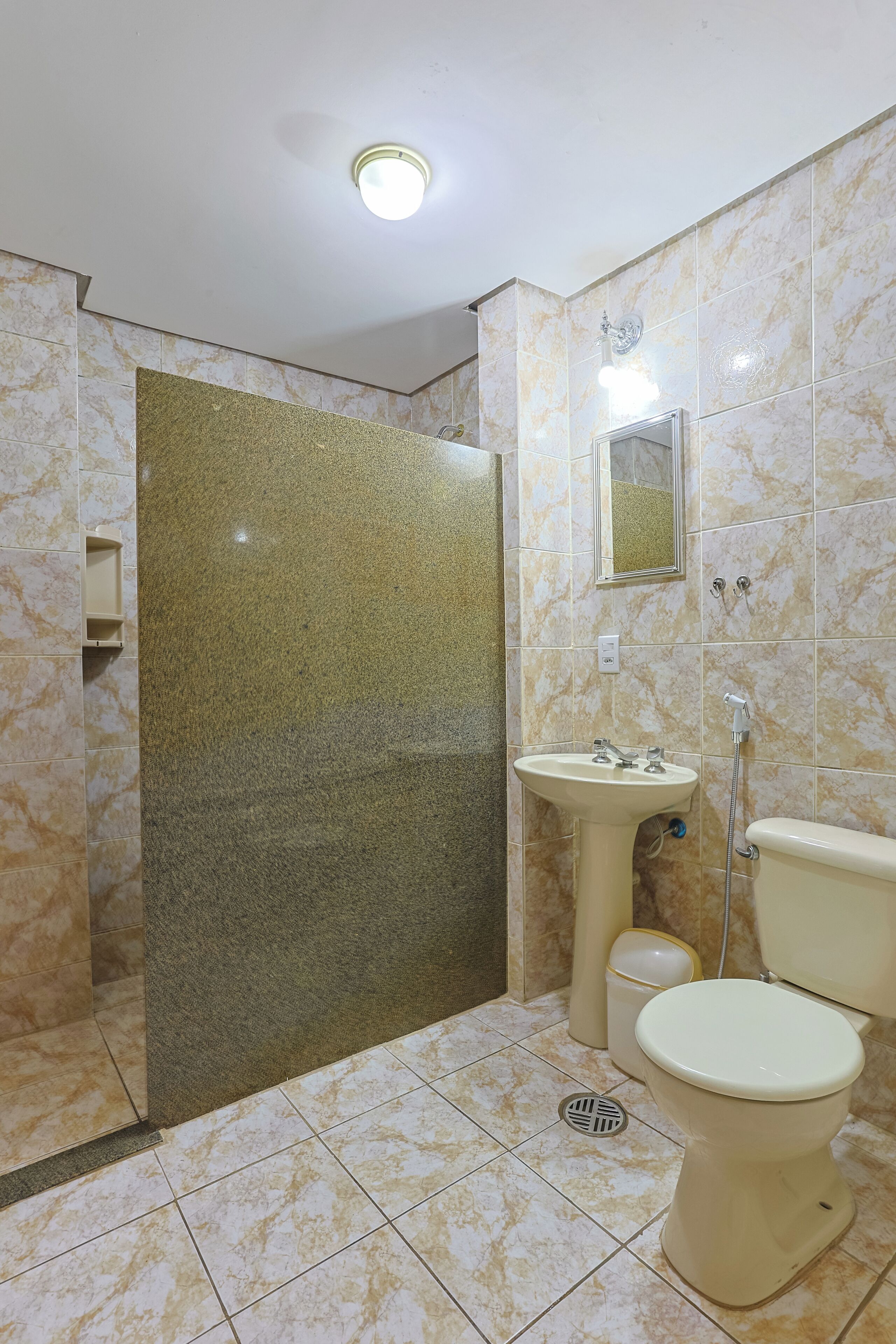 A bathroom with a marble floor, a sink, a toilet, and a shower.