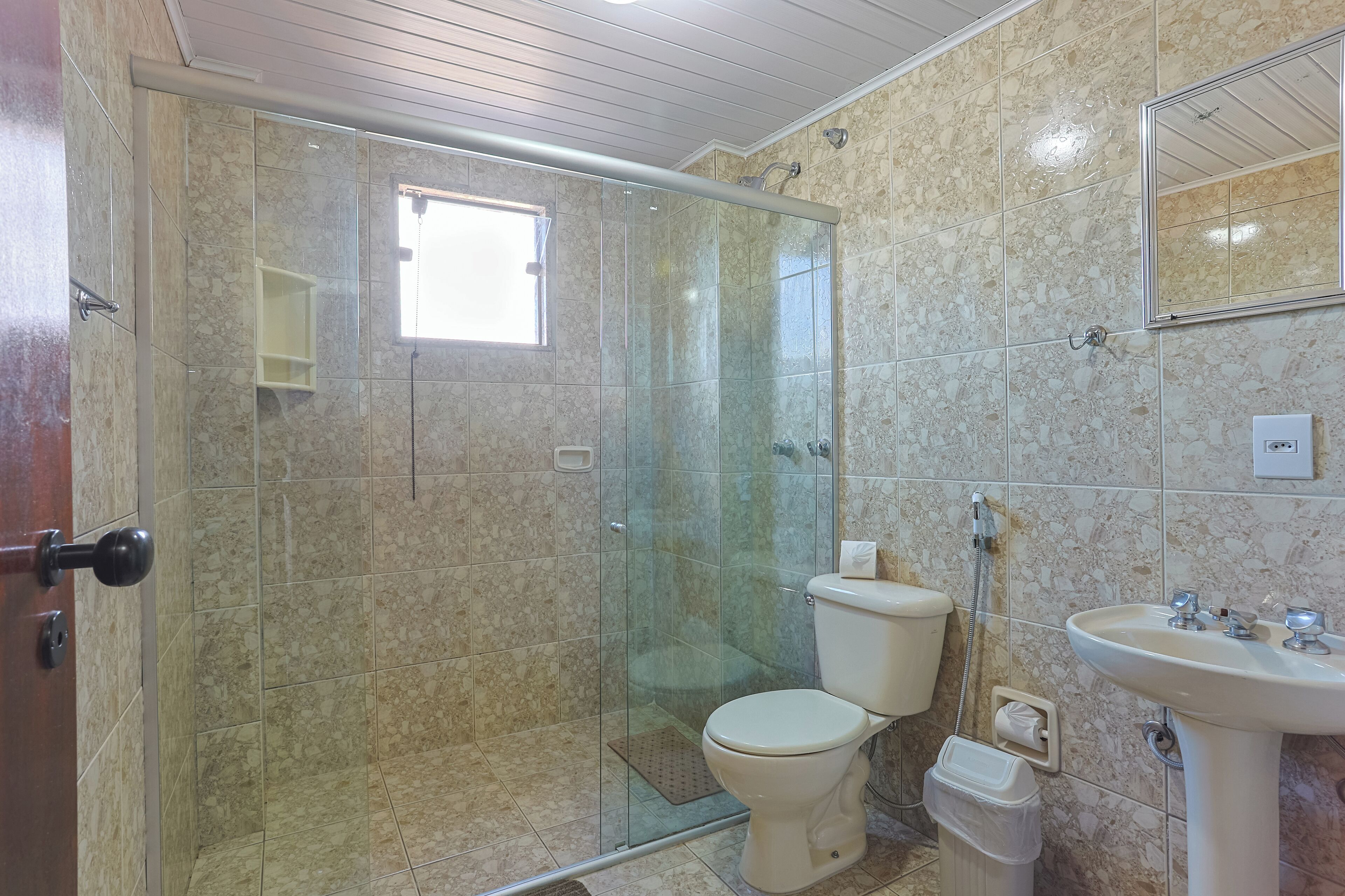 Une salle de bain avec une douche à parois de verre, des toilettes et un lavabo.