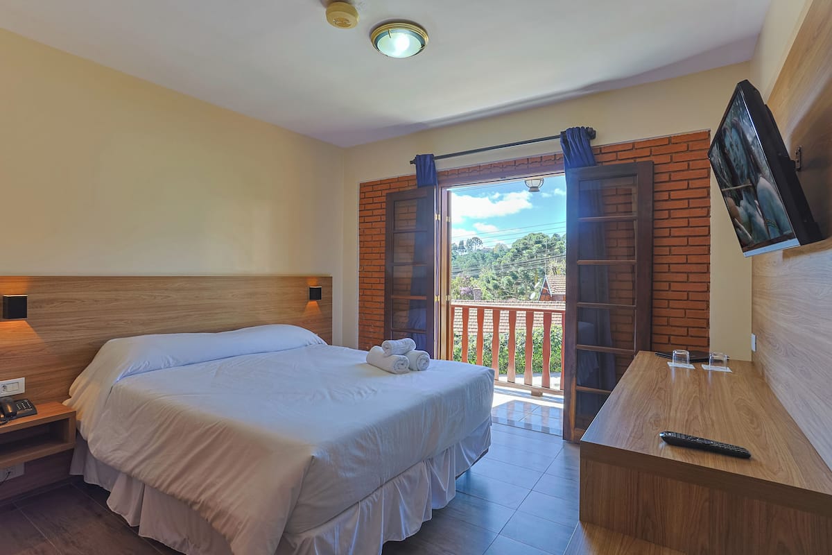 A hotel room with a bed, bedside table, and a desk with a chair.