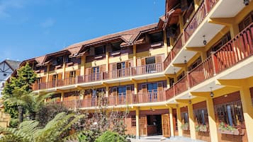 Stunning hotel with balconies and a tiled roof, set amidst a beautifully maintained garden.