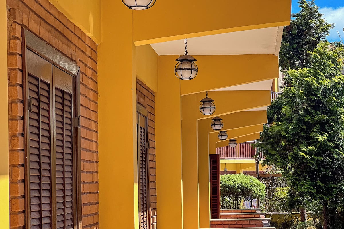 A corridor with yellow walls, brick columns, and hanging lanterns.