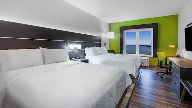 Une chambre d’hôtel avec deux lits, un bureau, une chaise et une grande fenêtre donnant sur un beau paysage.