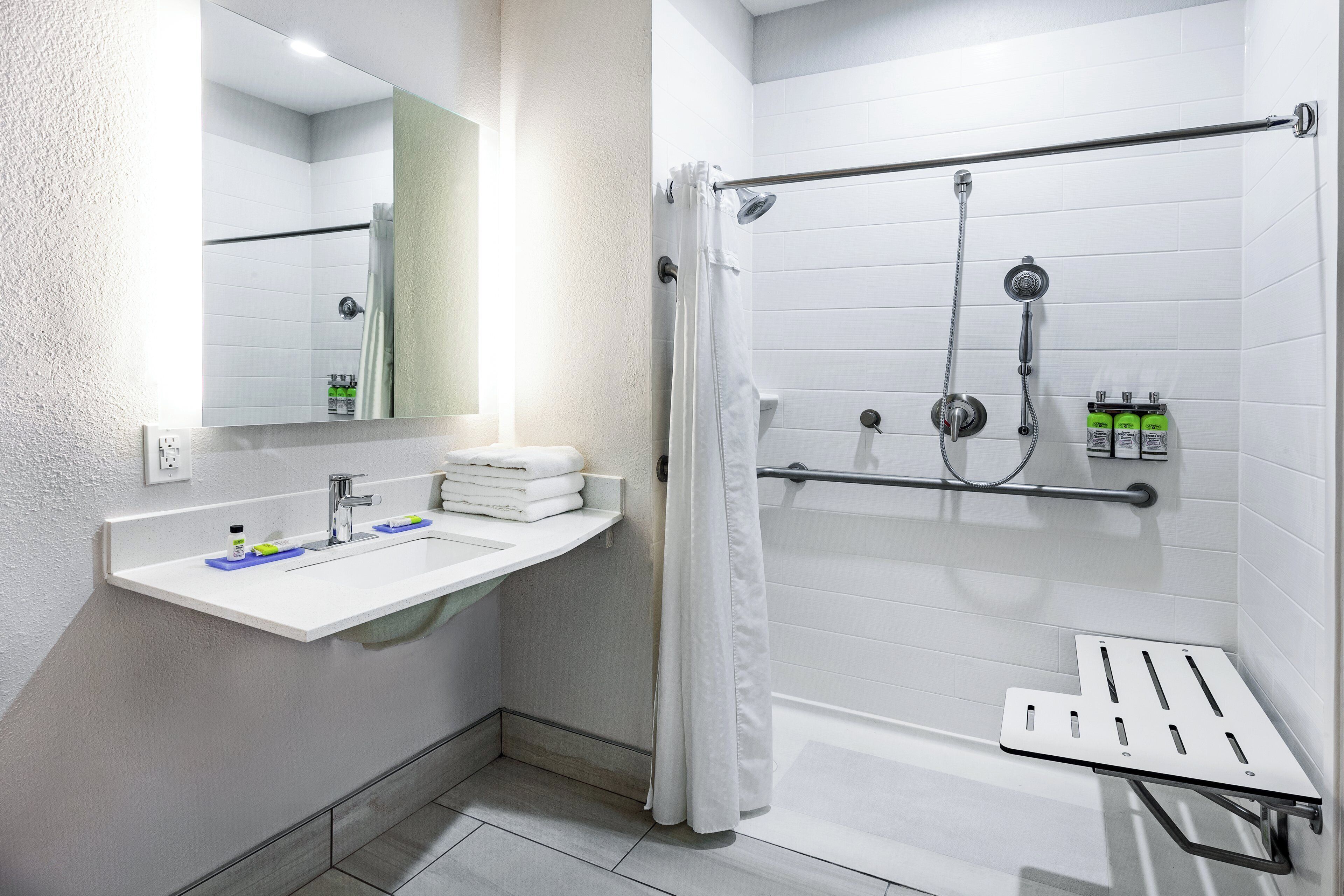 Un baño moderno con lavamanos blanco, espejo y zona de ducha.