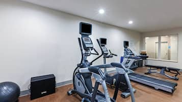 Een fitnessruimte met loopbanden, elliptische trainers en een roeimachine.