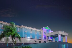 Un hotel con fachada moderna, múltiples ventanales y un llamativo letrero de Holiday Inn Express Suites.