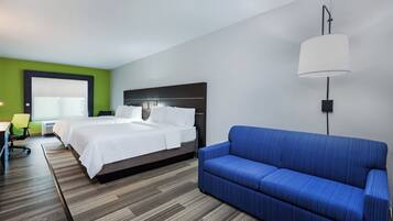 Una habitación de hotel con una cama, un sofá azul, un escritorio con una silla y una lámpara.