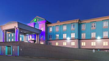 A hotel with a modern design, featuring a prominent entrance with a covered area and a sign indicating it is a Holiday Inn Express & Suites.