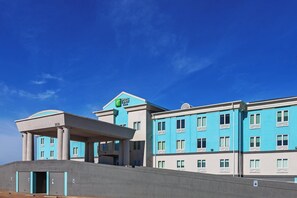 A hotel with a blue facade, multiple windows, and a covered entrance area.