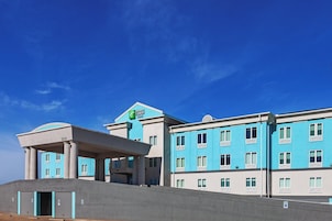 Un hotel con fachada azul, múltiples ventanas y un área de entrada cubierta.