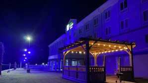 Un bâtiment doté d’une terrasse extérieure couverte, d’une enseigne indiquant qu’il s’agit d’un Holiday Inn Express, et d’une façade bien éclairée.