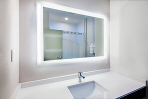A modern bathroom with a large mirror, a white sink, and a shower area. - Holiday Inn Express & Suites Port Lavaca by IHG (Port Lavaca)