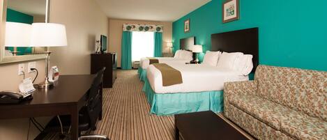 A hotel room with a bed, a desk with a telephone, a chair, a sofa, and a mirror.