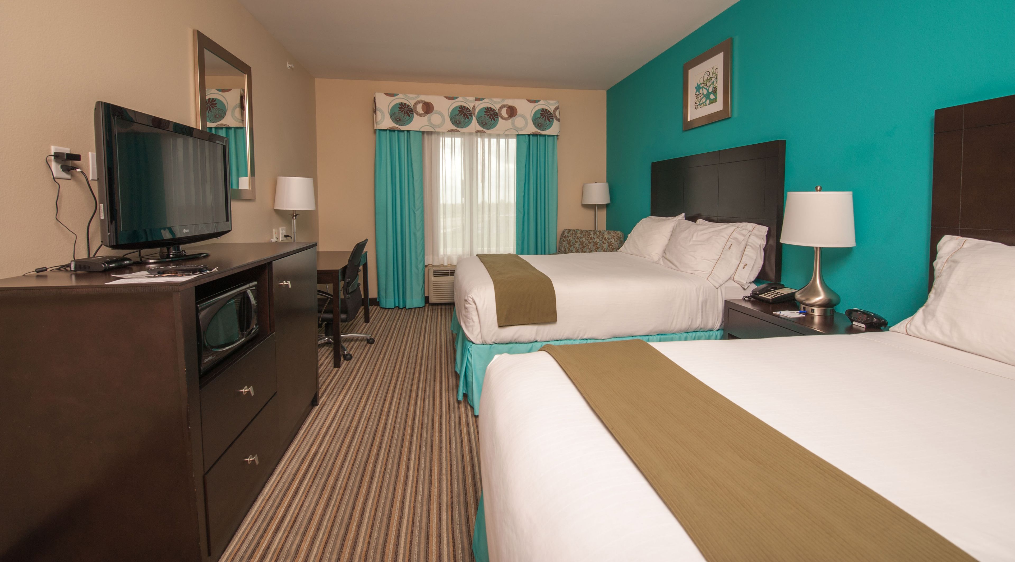 A hotel room with two beds, a desk, a television, and a minibar.