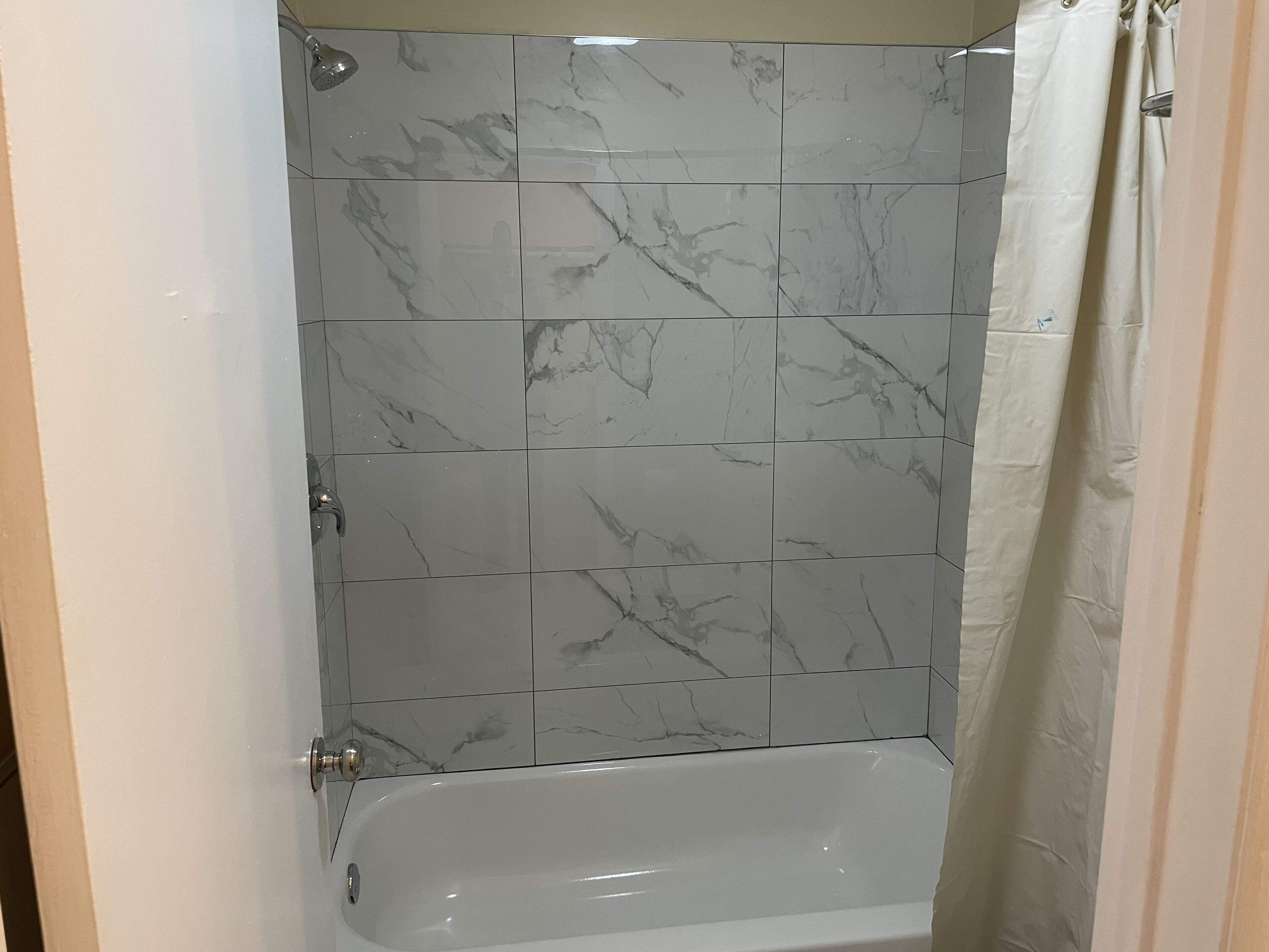 Ein Badezimmer mit einer Badewanne, gefliesten Wänden und einer Duschvorhang.