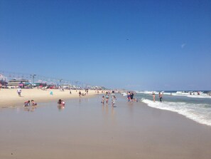 A beach with people, umbrellas, and a lifeguard tower. - Sea Palace Motel (Seaside Heights)