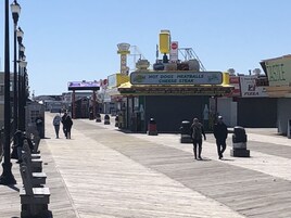 Un paseo marítimo con tiendas y un letrero que dice 'Hot Dogs, Meatballs, Cheese Steak'.