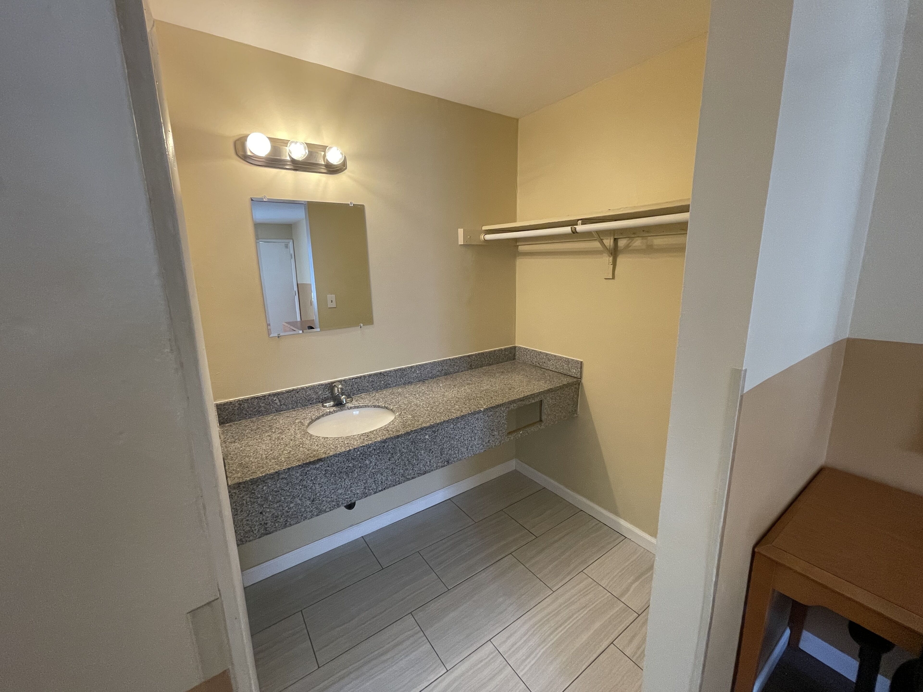 A bathroom with a sink, mirror, and towel rack.