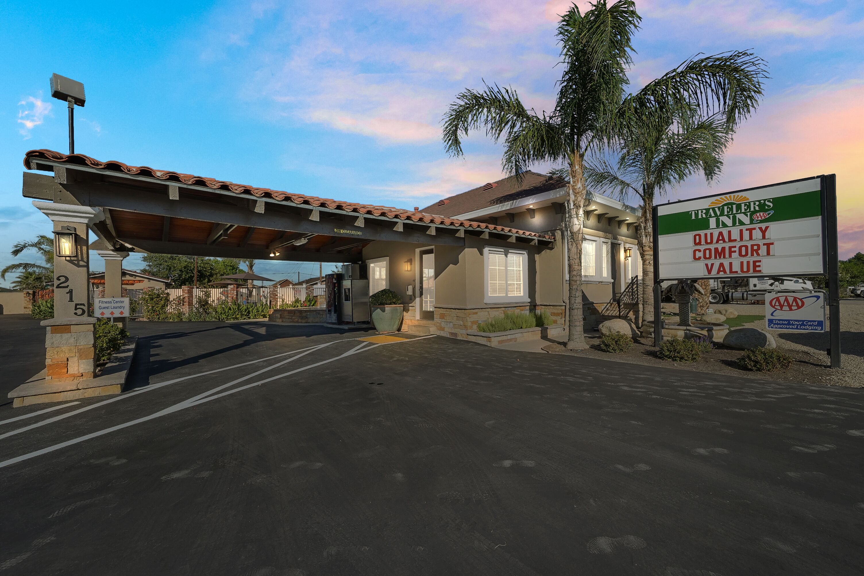 A hotel with a covered entrance, a sign for Traveler's Inn, and a AAA Approved Lodging sign.