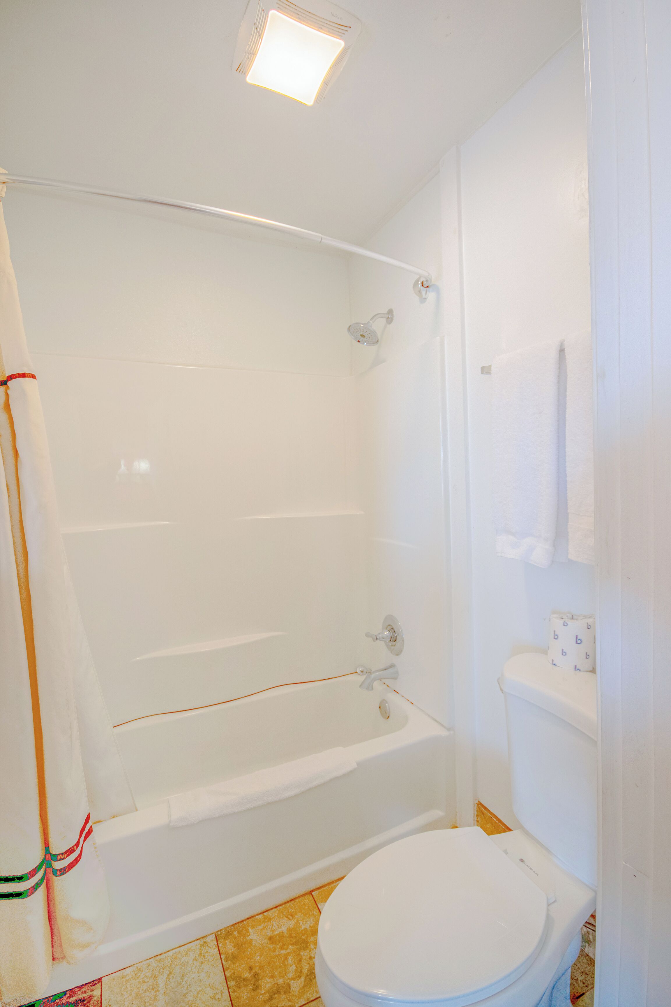 A bathroom with a bathtub, toilet, and a shower area.