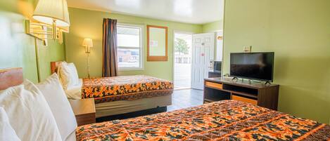 A hotel room with two beds, a television, and a window with curtains.