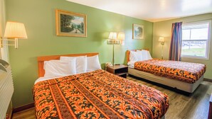 A hotel room with two beds, green walls, and artwork.