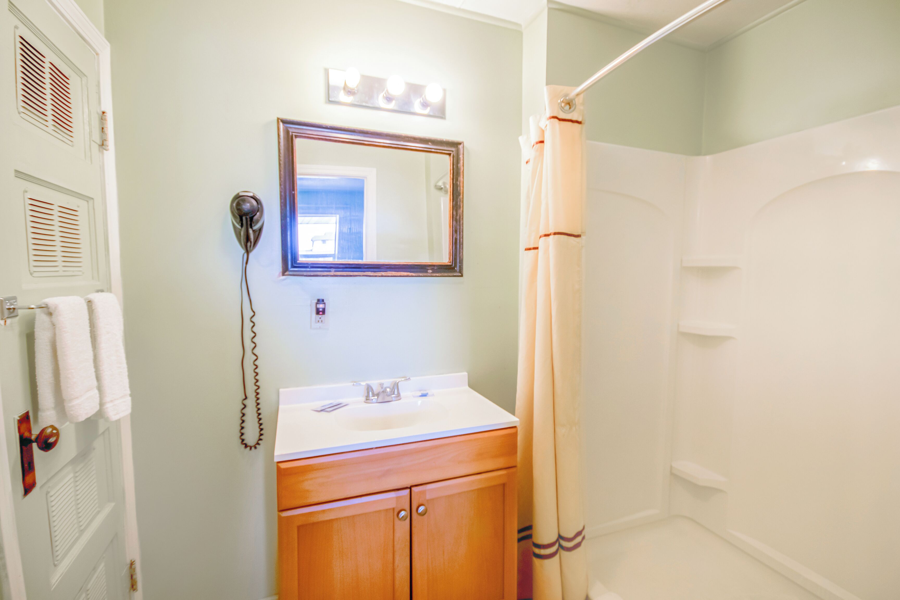A bathroom with a sink, mirror, and shower curtain.
