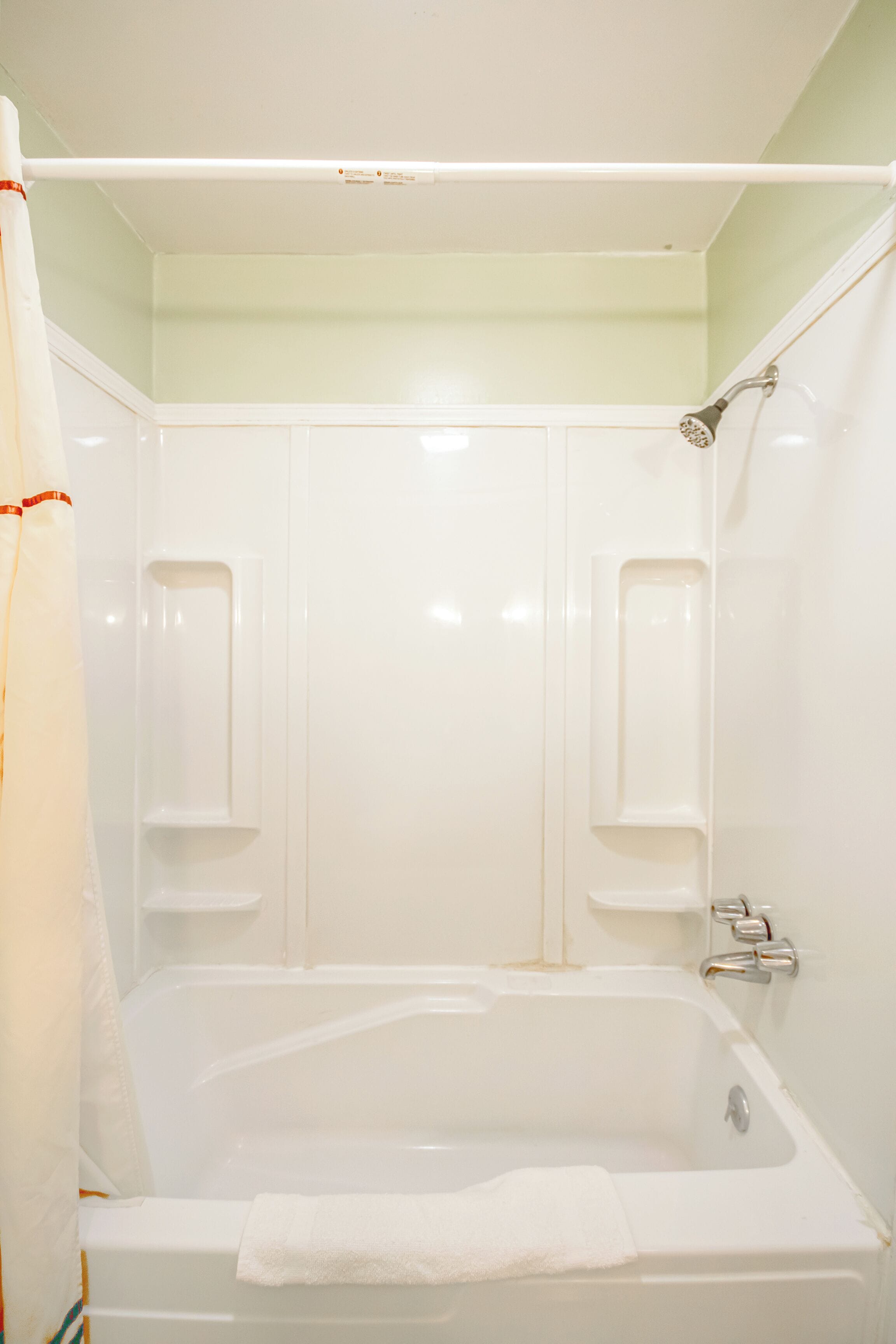 A white bathtub with a showerhead and a towel.