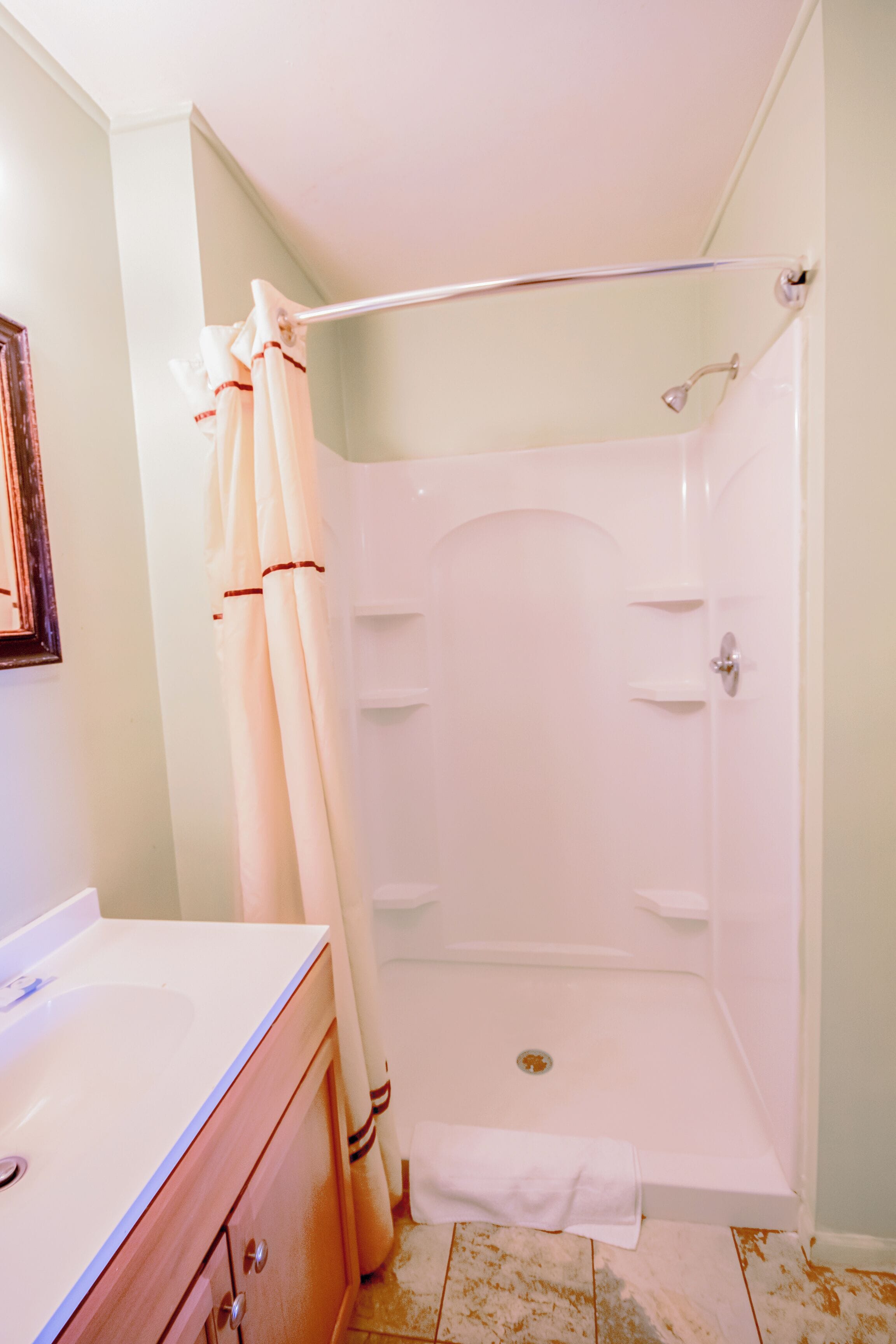 Un baño con ducha, lavamanos y espejo.