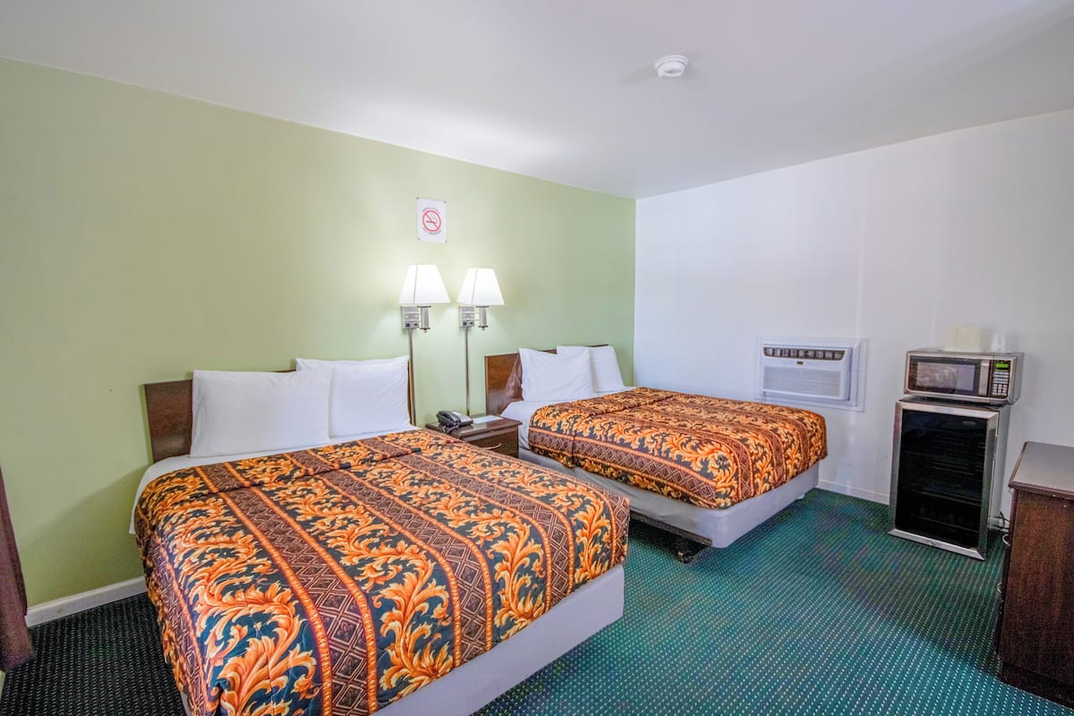 Quarto de hotel com duas camas, micro-ondas, uma pequena TV e telefone.