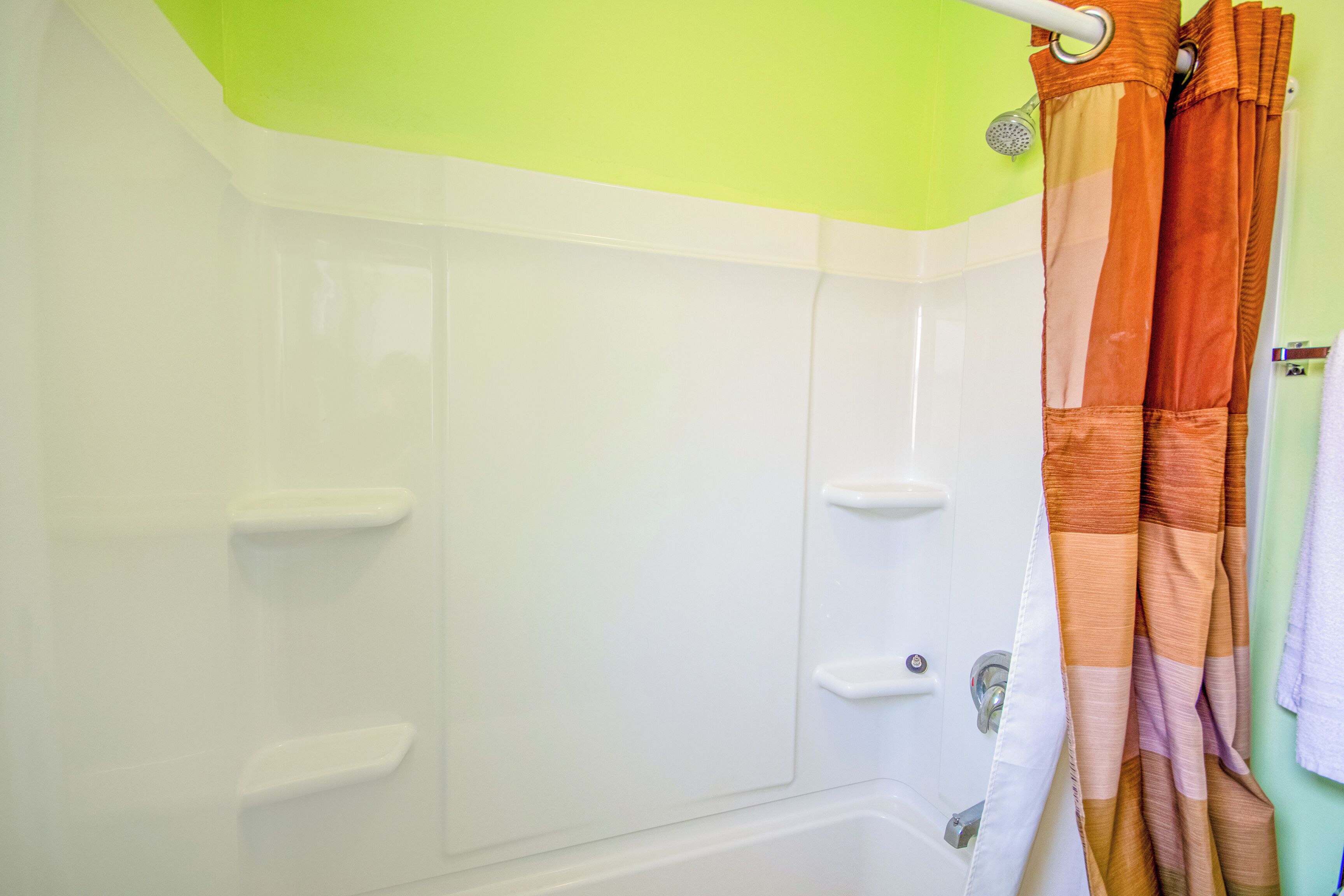 A shower area with a white bathtub, a showerhead, and a curtain.