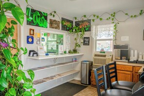 Un espace d’accueil comprenant un comptoir, une poubelle et un coin salon avec des chaises.