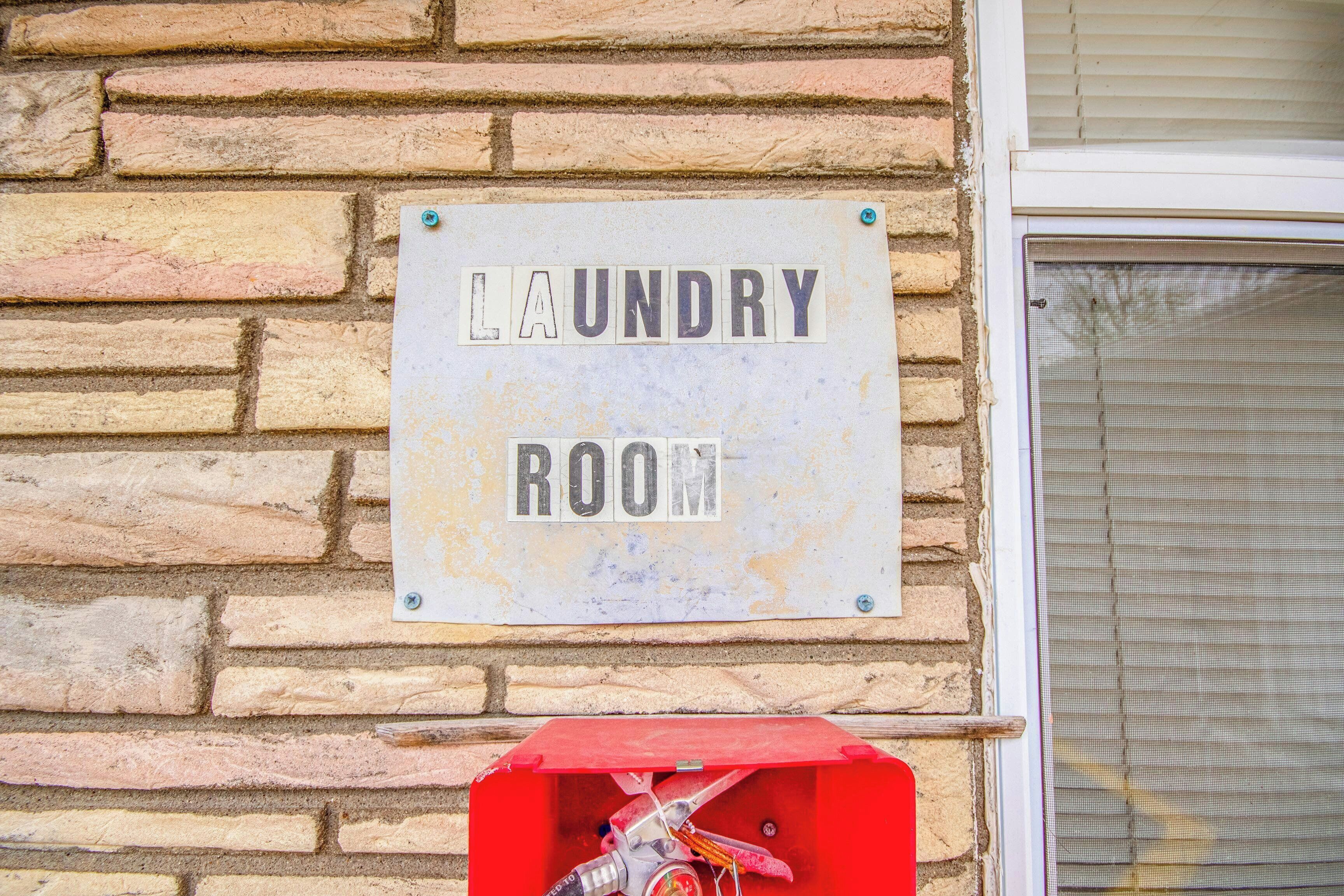 Segnaletica su un muro di mattoni con la scritta 'LAUNDRY ROOM'.