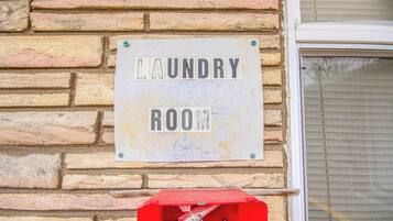 Segnaletica su un muro di mattoni con la scritta 'LAUNDRY ROOM'.