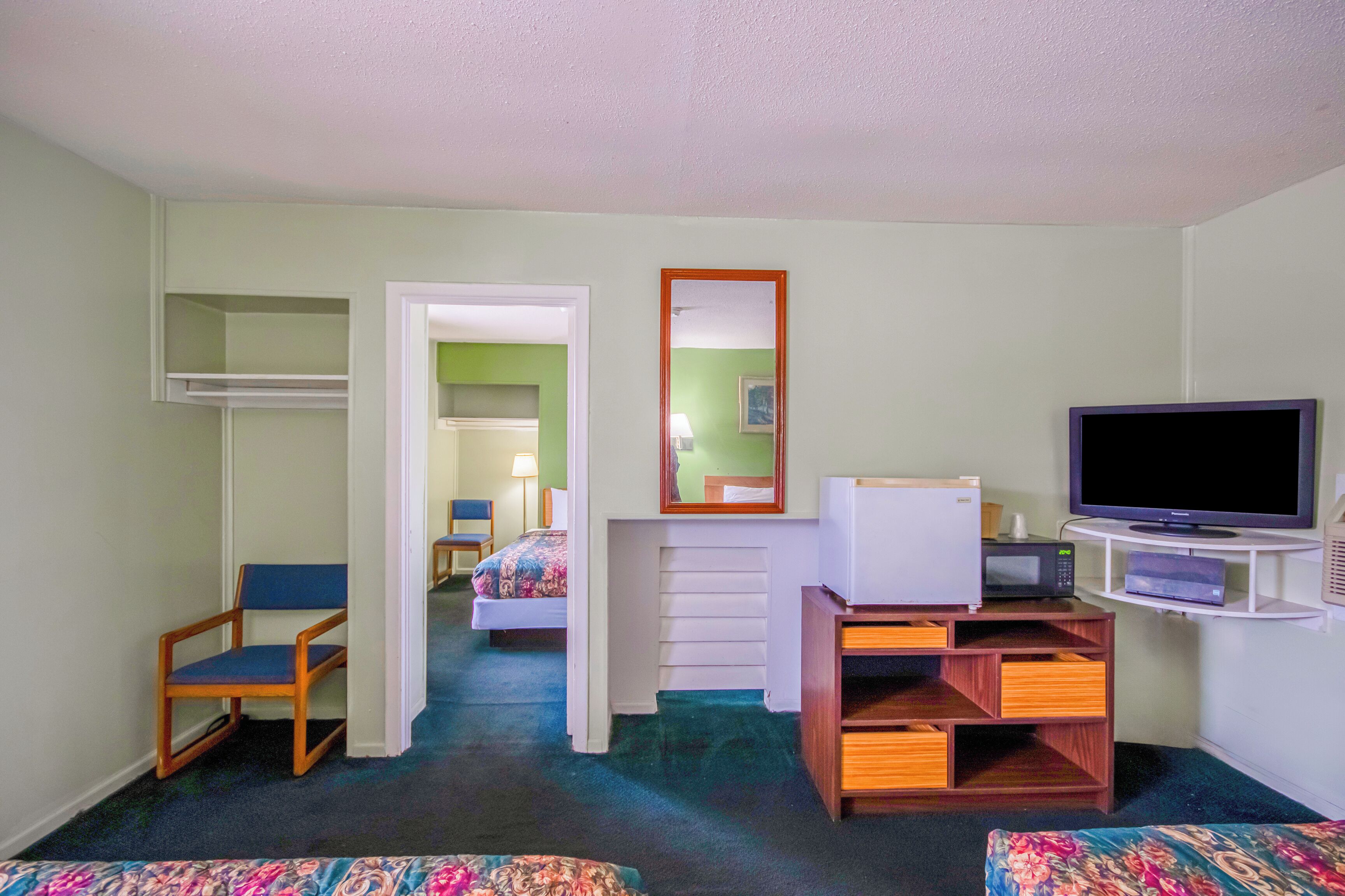 A hotel room with a bed, a chair, a television, a microwave, and a small desk.