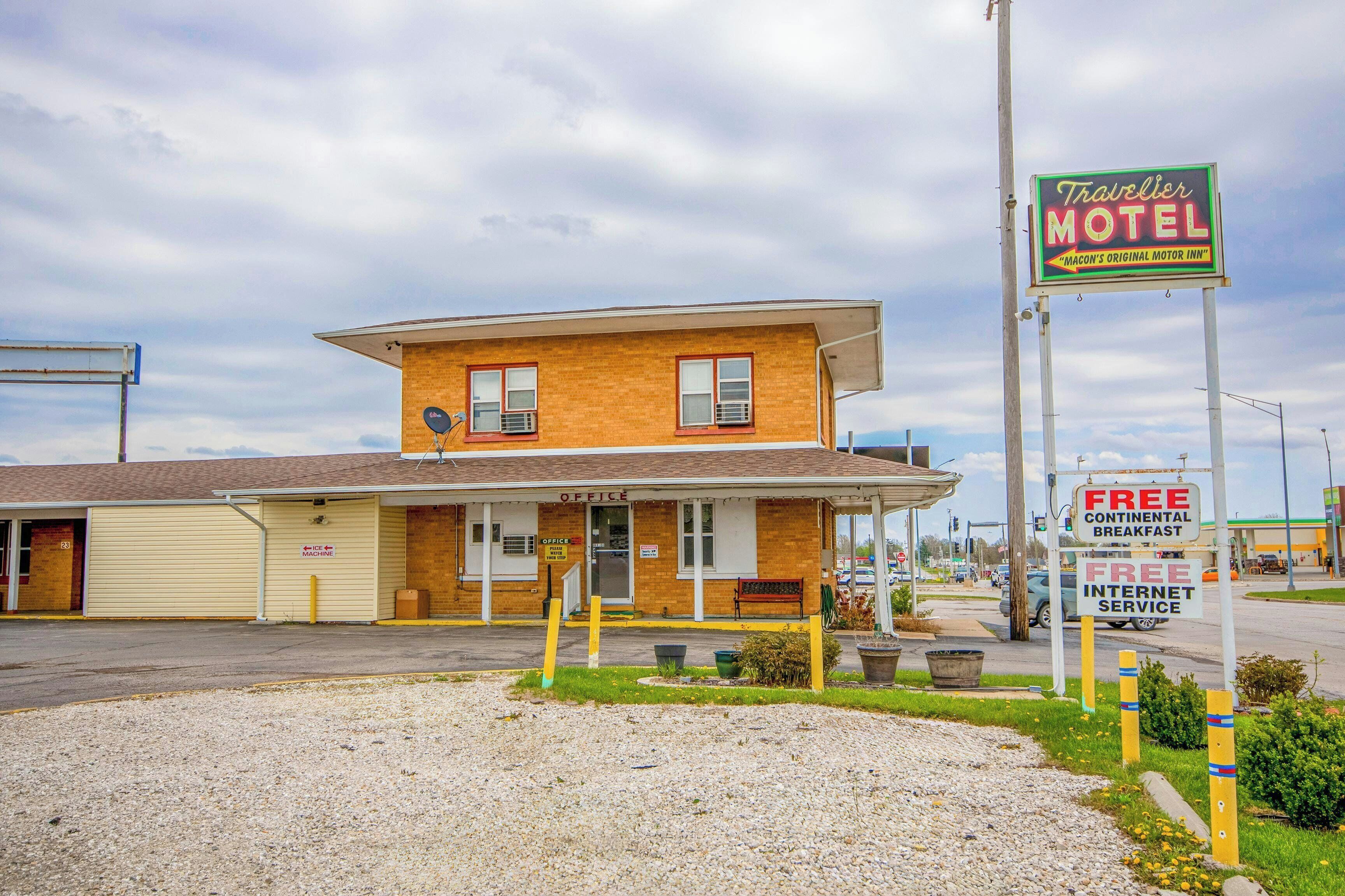 A two-story motel with a prominent sign, a small office, and a parking lot.