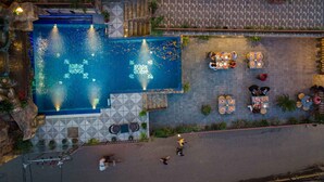An aerial view of a hotel pool area with a tiled deck, lounge chairs, and a fountain. - Hotel Manang (Kathmandu)