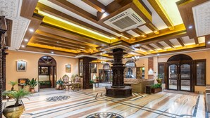 A spacious lobby with a marble floor, a central column, and a chandelier. - Hotel Manang (Kathmandu)