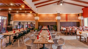 A restaurant with a long communal table, individual tables, and modern chairs. - Hotel Manang (Kathmandu)