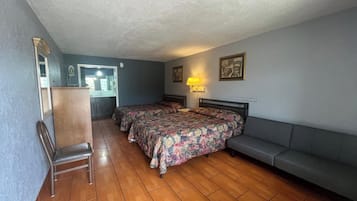 Una habitación con dos camas, una silla, un sofá, un escritorio y un espejo.
