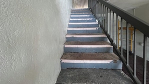 Eine Treppe mit abgenutzten Stufen und einem Metallgeländer, die zu einer höheren Etage führt.