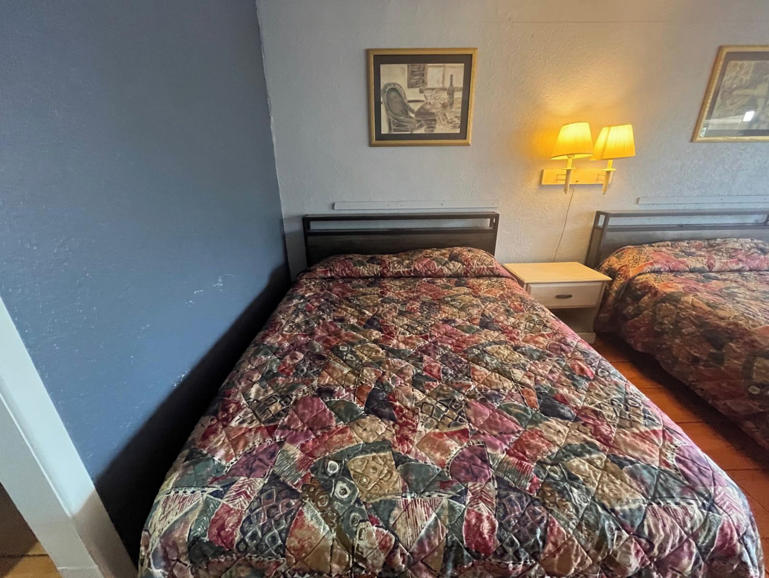 A room with a bed, a nightstand, and a lamp.