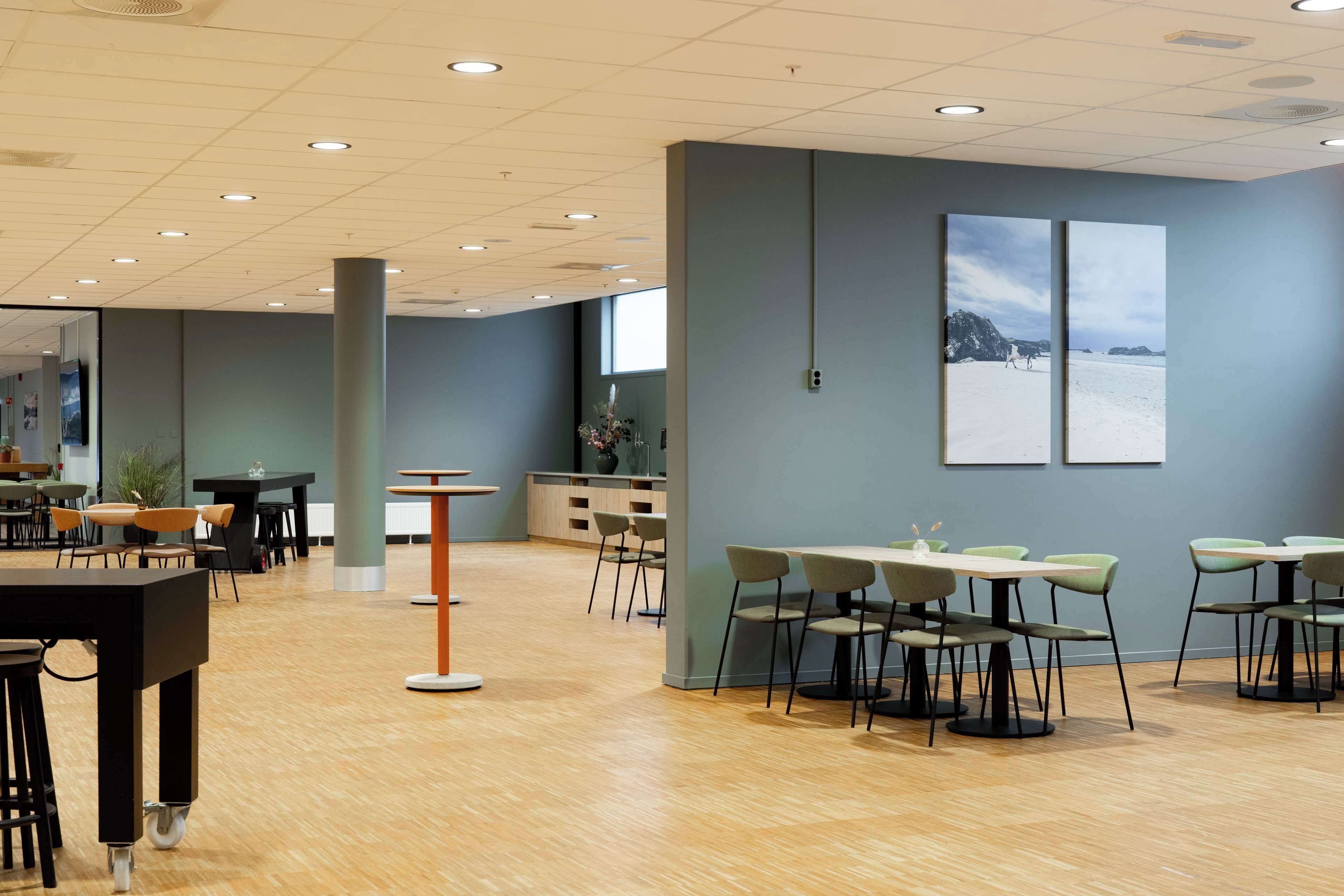 A spacious indoor area with multiple tables and chairs, a central pillar, and artwork on the walls.