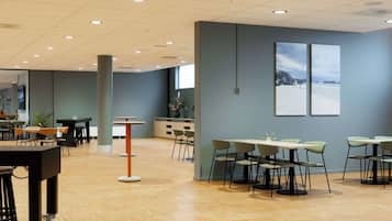 A spacious indoor area with multiple tables and chairs, a central pillar, and artwork on the walls.