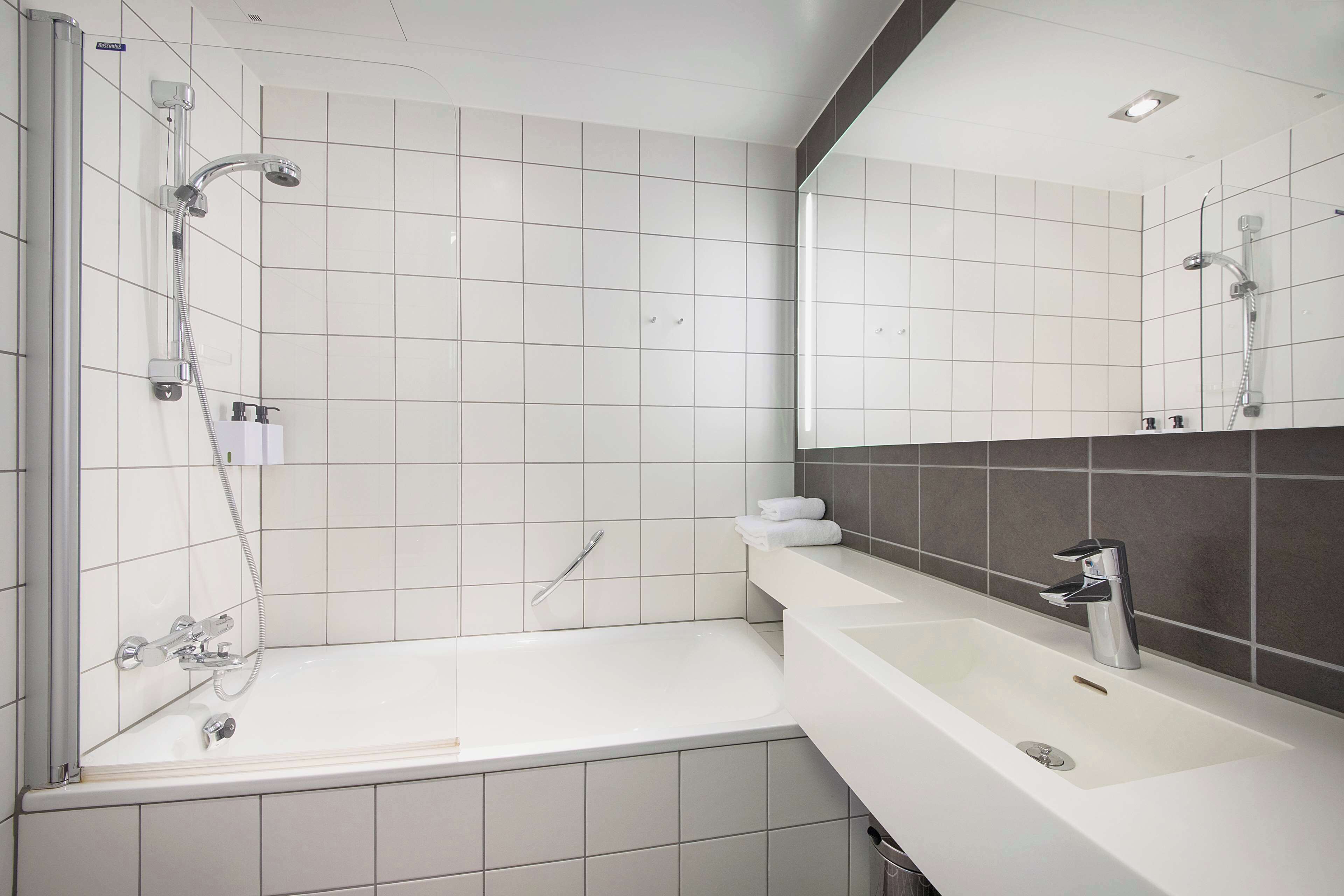 A modern bathroom with a bathtub, a shower, and a sink.