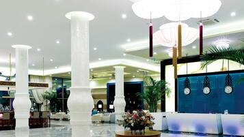 A spacious lobby with high ceilings, large white columns, and a central round table with a floral arrangement.