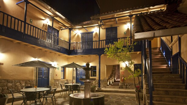Un patio con una fuente, mobiliario exterior y una escalera que conduce a un nivel superior.