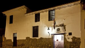 Un edificio blanco con paredes de piedra, una puerta de madera y una escalera que conduce a la entrada.
