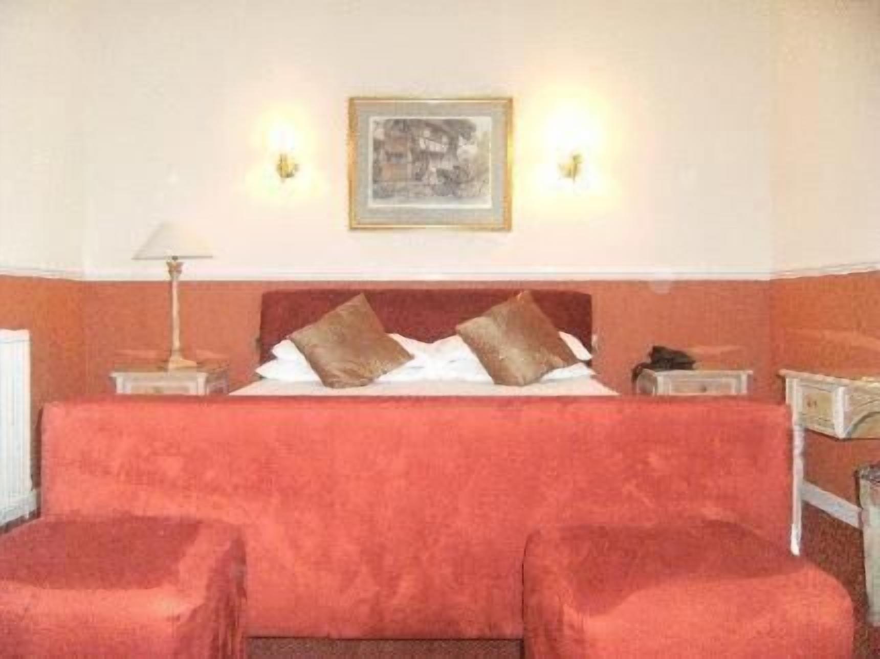 A hotel room with a large bed, two bedside tables, a nightstand, and a framed picture on the wall.