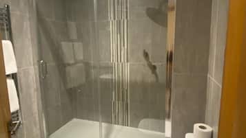 Un baño moderno con ducha de vidrio, inodoro y toallero.