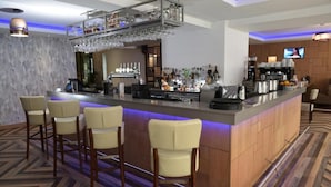 Un espace bar doté d’un long comptoir, de tabourets de bar et d’une variété de bouteilles et de verres.